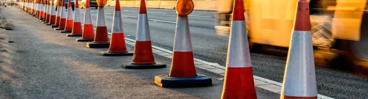 Une rangée de cônes de signalisation orange et blancs délimite une zone sur le bord d'une route.
