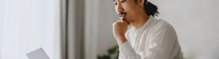 Un homme assis sur un canapé, concentré sur son ordinateur portable.