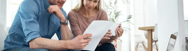 Couple en train de lire des documents sur leur canapé.