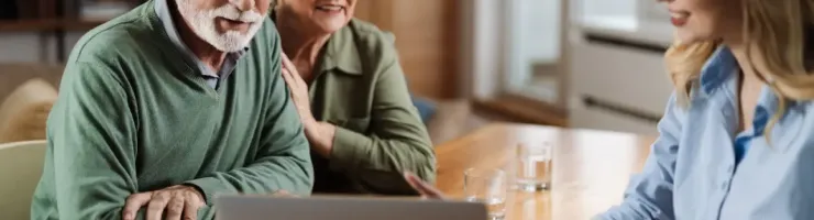 Un couple âgé est en train de discuter avec une conseillère. Elle utilise un ordinateur portable pour appuyer ses propos.