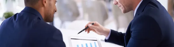 Deux hommes d'affaires sont en pleine discussion formelle devant une tablette.
