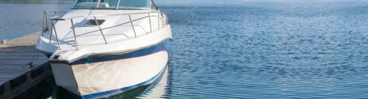Bateau blanc et bleu amarré à un ponton d'un lac paisible.