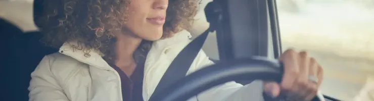 Une femme avec des cheveux bouclés conduisant une voiture.
