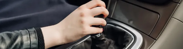 Gros plan d'une main changeant les vitesses sur un levier de vitesse manuel à l'intérieur d'une voiture.