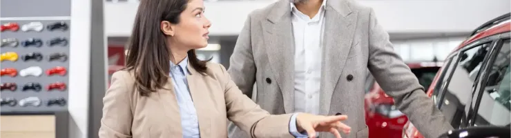 Une vendeuse de voitures explique quelque chose à un client masculin dans un showroom.