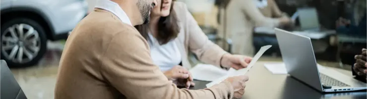 Un couple examine des documents avec un conseiller automobile dans une concession.