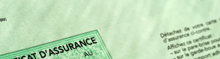 Gros plan sur un certificat d'assurance automobile vert affichant les dates de validité et des informations.