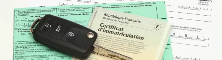 Une clé de voiture est posée sur des documents administratifs français, incluant un certificat d'immatriculation.