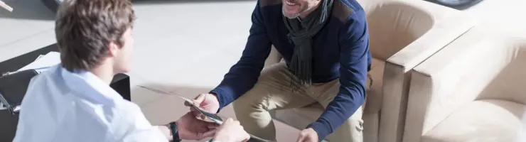 Un commercial d'une consession automobile et un acheteur sont assis et discutent