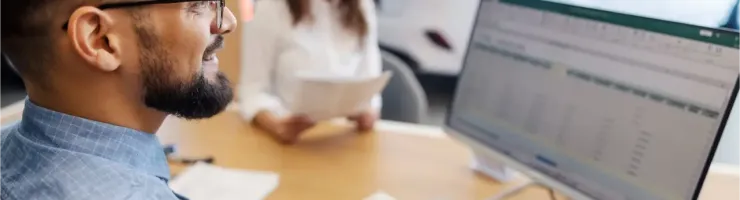 Un vendeur et une cliente discutent, le vendeur utilisant un ordinateur, dans une concession automobile.