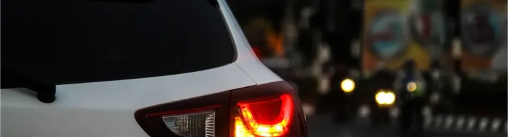 Gros plan sur le feu arrière droit allumé d'une voiture blanche au crépuscule en ville.