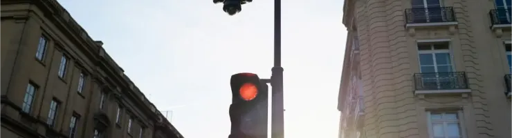 Un feu de circulation rouge et un réverbère devant des immeubles haussmanniens à Paris.