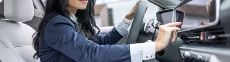 Une femme d'affaires dans une voiture moderne, consultant son tableau de bord avec concentration.