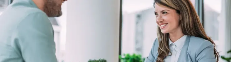 Une conseillère avec des documents discute avec un homme assis à un bureau.