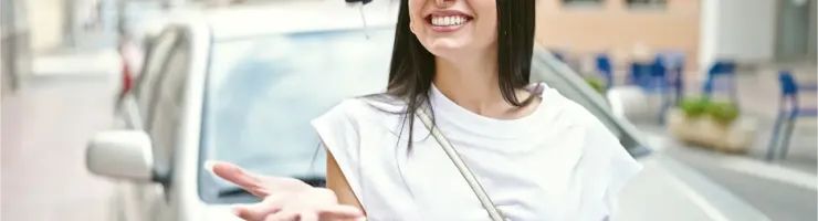 Une femme attrape sa clé de voiture, se tenant devant son véhicule.