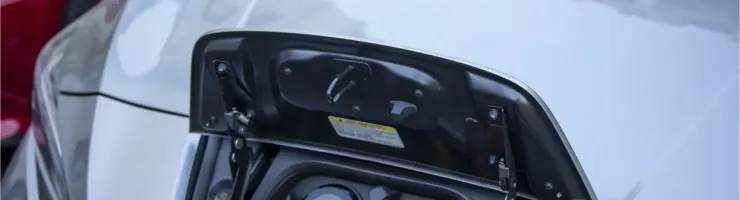 Gros plan sur le port de charge d'une voiture électrique grise avec le câble branché.