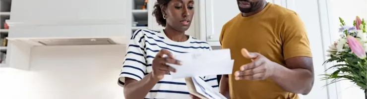 Dans une cuisine, un couple consulte des documents envoyés par courrier.
