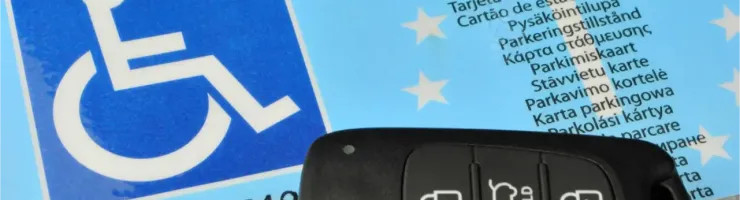 Carte de stationnement pour personne handicapée et clé de voiture sur un fond bleu.