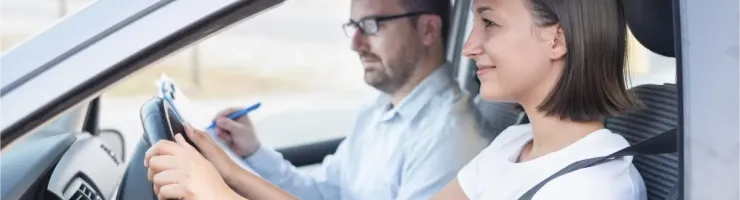 Jeune femme souriante apprenant à conduire avec un instructeur attentif dans une voiture.