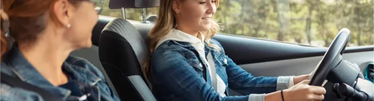 Une mère apprend à sa fille à conduire un véhicule.