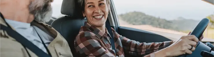Un couple souriant conduisant une voiture.