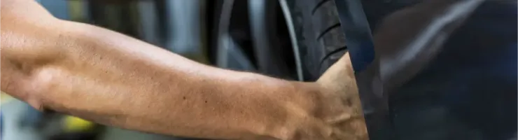 Gros plan sur les mains d'un homme installant un pneu de voiture.