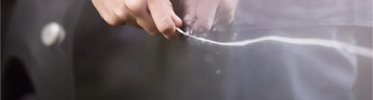 Gros plan des mains rayant délibérément la peinture d'une voiture avec une clé, laissant une trace claire.