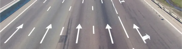 Vue aérienne d'une autoroute à plusieurs voies avec des flèches directionnelles peintes sur l'asphalte.