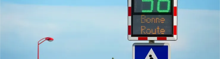 Un panneau radar pédagogique en France affiche "VOUS ROULEZ A 38" et "Bonne Route" au-dessus d'un passage piéton.