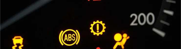 Gros plan sur le tableau de bord d'une voiture avec plusieurs voyants d'alerte allumés.