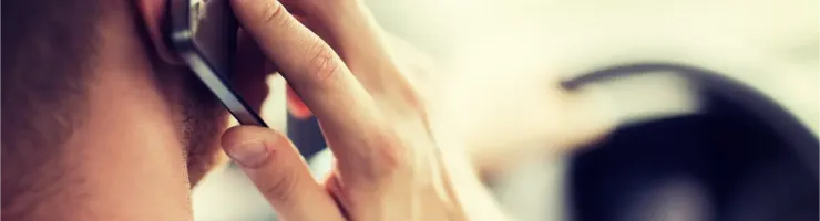 Vue arrière d'un homme en costume tenant un téléphone portable à son oreille en conduisant.