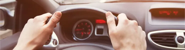 Vue subjective d'une personne conduisant une voiture sur une autoroute encombrée au lever du soleil.