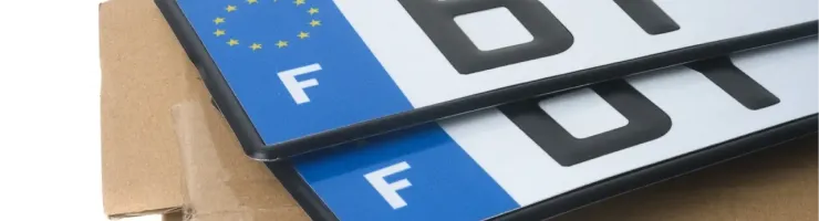Deux plaques d'immatriculation françaises neuves avec le drapeau de l'UE et la lettre 'F', sur une boîte.