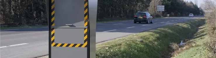 Un radar automatique français avec des bandes jaunes et noires au bord d'une route.