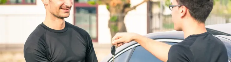 Un homme souriant reçoit les clés d'une voiture d'un autre homme.