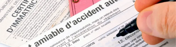 Une main remplit un constat amiable d'accident automobile sur des documents officiels.