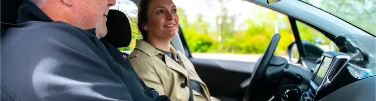 Un examinateur et un candidat en voiture, l'examinateur utilisant un boîtier de contrôle.