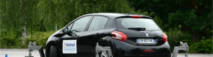 Une voiture Peugeot 208 noire avec des stabilisateurs pour un stage de conduite.