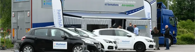 Des voitures de formation Matmut et un camion remorque sont stationnés sur un parking.