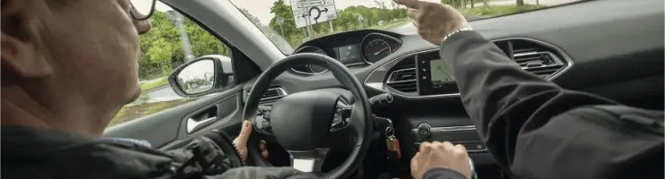 Deux personnes à l'intérieur d'une voiture, l'une pointant du doigt quelque chose à l'extérieur.