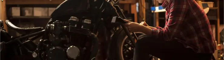 Une jeune femme mécanicienne concentrée travaille sur une moto dans un garage bien équipé.