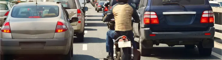 Un motard remonte une file de voitures dans les embouteillages.