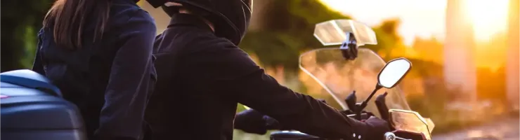 Un couple en casque sur une moto de tourisme au coucher du soleil, profitant de la balade.