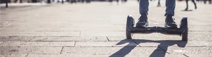 Gros plan sur les pieds d'une personne debout sur un hoverboard sur un trottoir pavé.