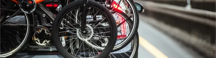 Des vélos sont attachés à un porte-vélos à l'arrière d'une voiture sur une route, vue arrière.