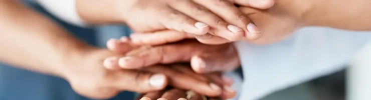 Mains empilées symbolisant la collaboration et le soutien mutuel.