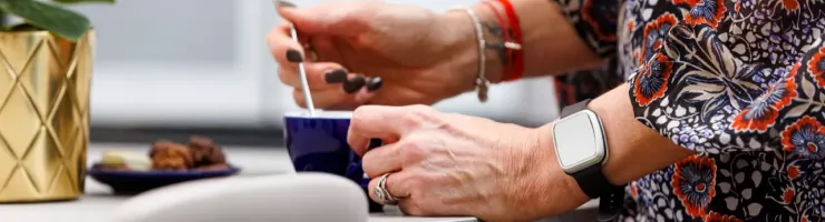 Gros plan sur les mains d'une femme mélangeant du sucre dans une tasse de café.