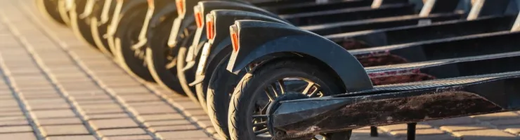 Des trottinettes électriques en ligne sur un trottoir en briques.