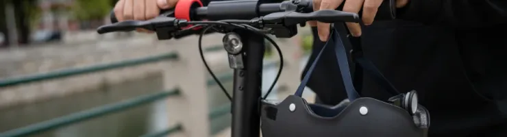 Une personne tient un casque sur une trottinette.