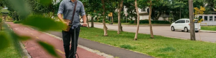 Un homme roule sur une trottinette électrique sur un chemin.